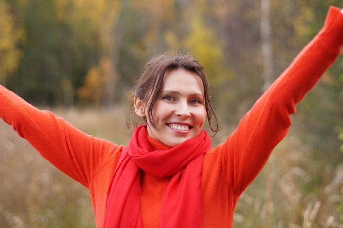 mujer joven feliz extiende brazos en otoño